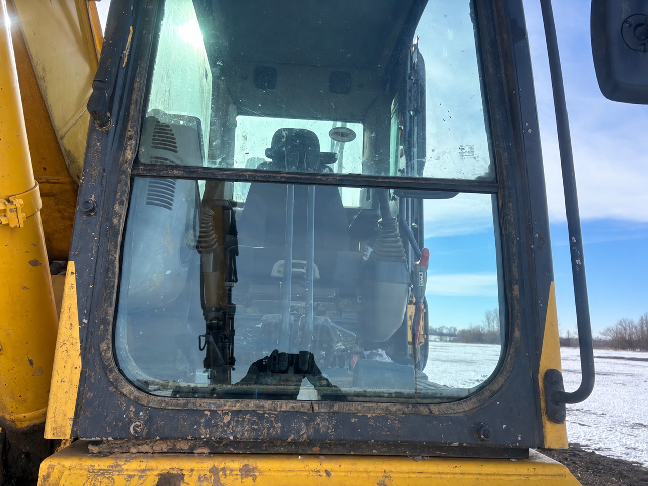 Close view of Komatsu excavator front cab glass with snow visible outside