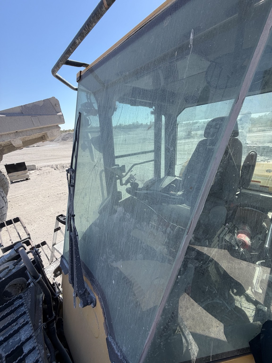 Close view of the cracked windshield on the Komatsu WA320 before replacement